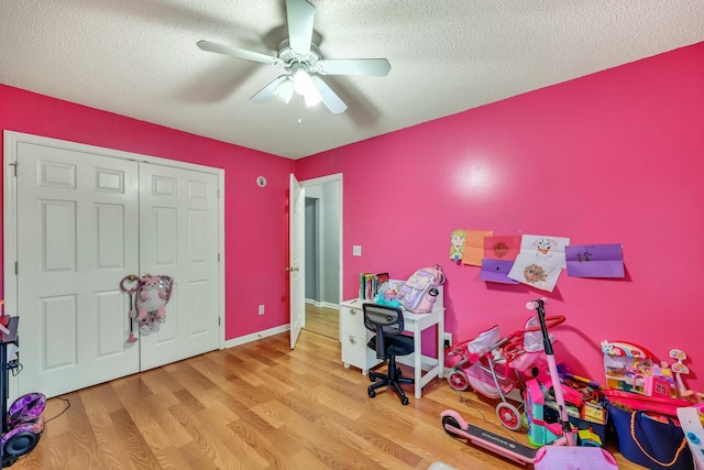 rec room featuring ceiling fan, light wood-type flooring, and a textured ceiling