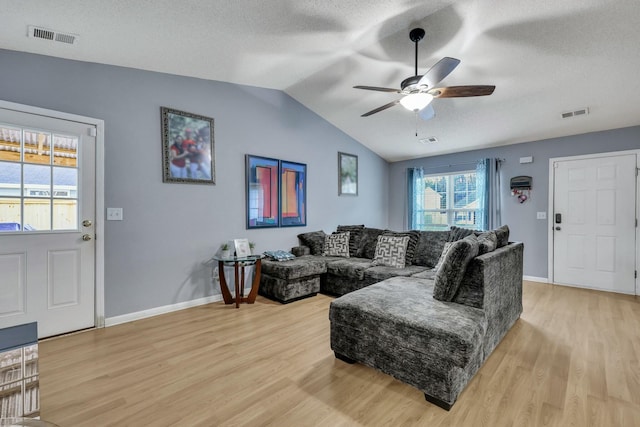 living room featuring light wood-type flooring, ceiling fan, lofted ceiling, and a textured ceiling