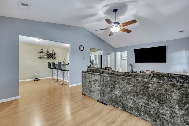 living room with ceiling fan, vaulted ceiling, and light wood-type flooring