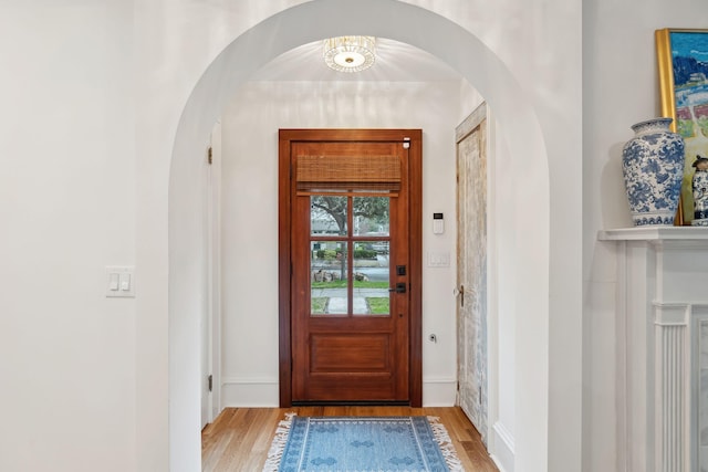 foyer with baseboards, arched walkways, and wood finished floors