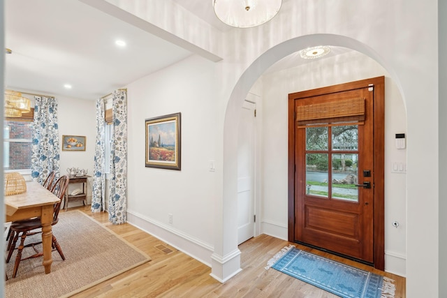 foyer featuring visible vents, recessed lighting, arched walkways, light wood finished floors, and baseboards