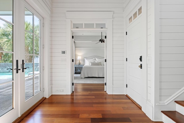 interior space with french doors, dark wood-type flooring, and wood walls