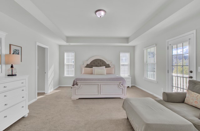 bedroom with light carpet, access to exterior, and a raised ceiling