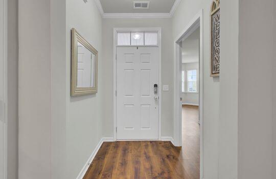 interior space with plenty of natural light, dark hardwood / wood-style floors, and ornamental molding