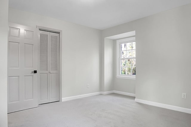 unfurnished bedroom featuring light colored carpet and a closet