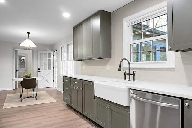 kitchen featuring sink, gray cabinetry, hanging light fixtures, stainless steel dishwasher, and light hardwood / wood-style floors