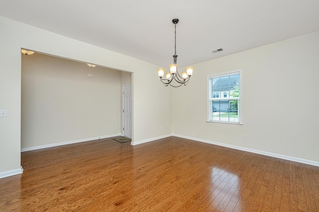 unfurnished room featuring wood-type flooring and a chandelier