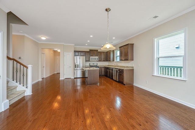 kitchen featuring hanging light fixtures, a center island, dark wood-type flooring, and stainless steel appliances