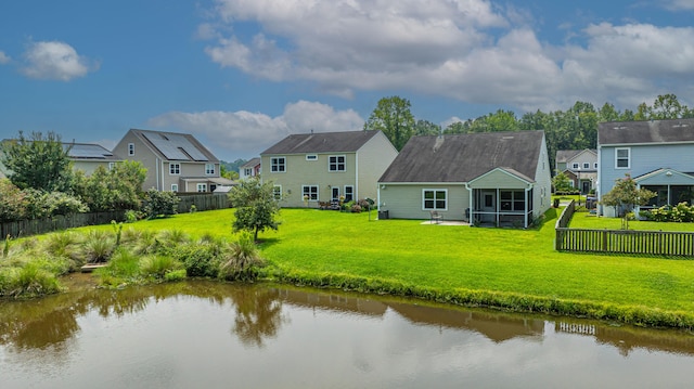 back of house with a yard, a sunroom, and a water view