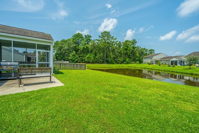 view of yard featuring a patio, a sunroom, and a water view