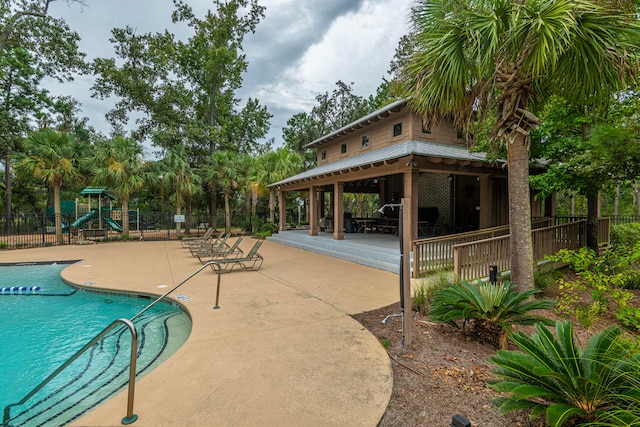 view of pool with a playground and a patio