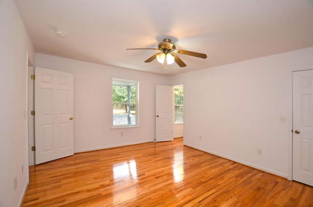 empty room with ceiling fan, light wood-style flooring, and baseboards