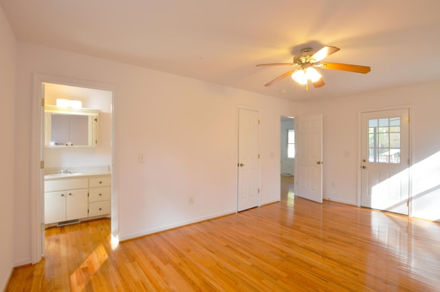 unfurnished living room featuring ceiling fan, baseboards, light wood-style flooring, and a sink