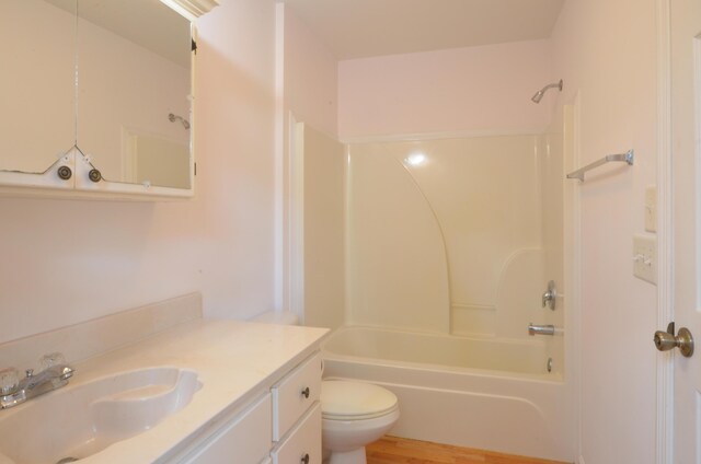bathroom with wood finished floors, toilet, bathtub / shower combination, and vanity