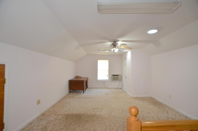 additional living space featuring lofted ceiling, a wall unit AC, carpet flooring, baseboards, and a ceiling fan