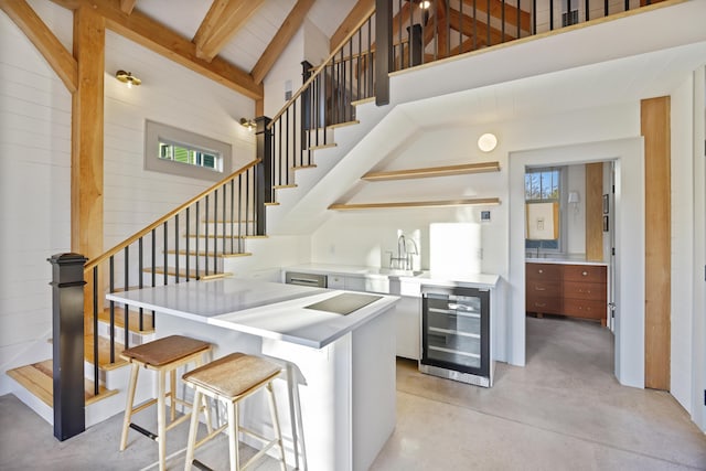 kitchen featuring high vaulted ceiling, beverage cooler, a sink, open shelves, and concrete floors