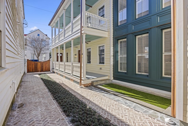 view of property exterior with covered porch, a balcony, and fence