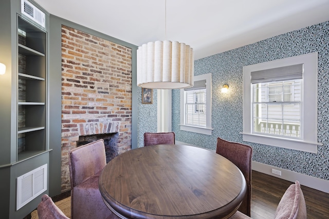 dining area featuring wallpapered walls, plenty of natural light, wood finished floors, and visible vents