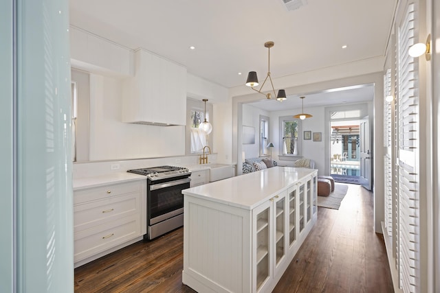 kitchen featuring dark wood-type flooring, a sink, white cabinetry, gas stove, and glass insert cabinets