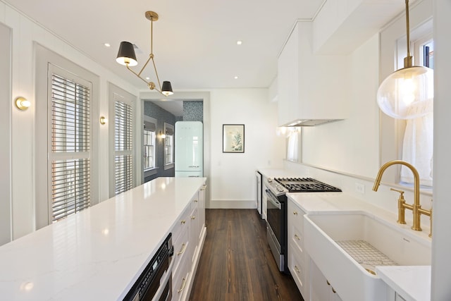 kitchen with light stone countertops, dark wood finished floors, a sink, white cabinetry, and gas range