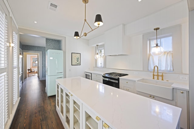 kitchen featuring plenty of natural light, gas stove, visible vents, and a sink