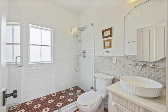 full bath with toilet, tile walls, vanity, and a tile shower