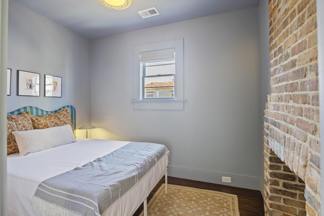 bedroom with wood finished floors, visible vents, and baseboards