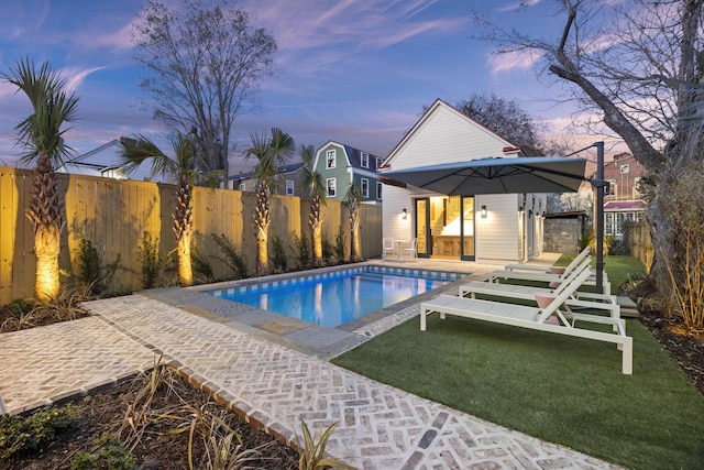 view of swimming pool with a lawn, an outdoor structure, a fenced backyard, and a fenced in pool