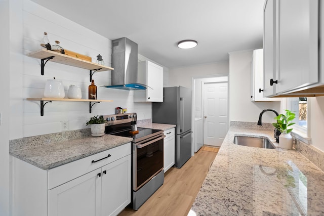 kitchen with wall chimney range hood, appliances with stainless steel finishes, a sink, light wood-type flooring, and open shelves