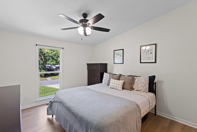 bedroom featuring wood finished floors, vaulted ceiling, baseboards, and ceiling fan