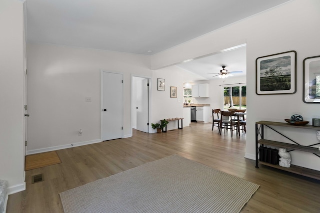 living room with ceiling fan, wood finished floors, baseboards, and lofted ceiling