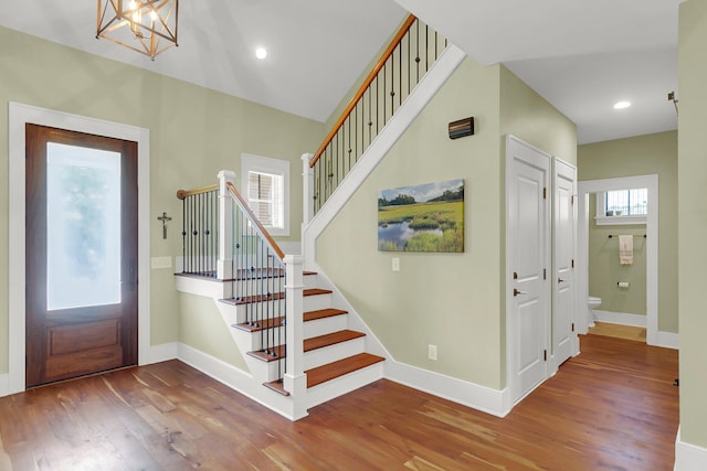 entrance foyer with a wealth of natural light, wood-type flooring, and a notable chandelier