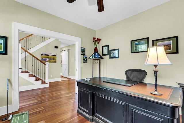 office space with a barn door, dark hardwood / wood-style floors, and ceiling fan