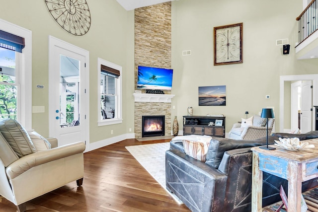 living room featuring a fireplace, a towering ceiling, and wood-type flooring