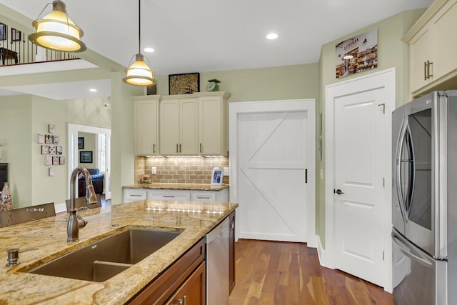 kitchen featuring light stone counters, appliances with stainless steel finishes, dark hardwood / wood-style floors, pendant lighting, and sink