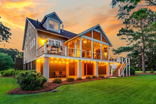 back house at dusk featuring a lawn