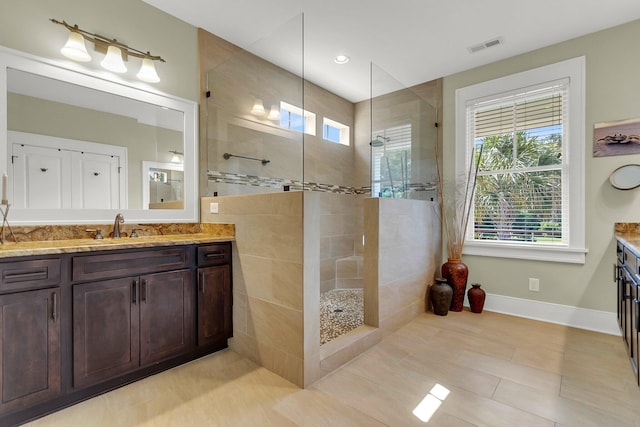 bathroom with tiled shower, tile patterned flooring, and vanity