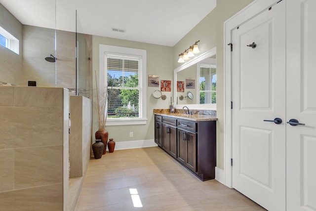 bathroom featuring vanity, a wealth of natural light, tile patterned flooring, and tiled shower