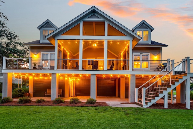 back house at dusk featuring a patio and a lawn