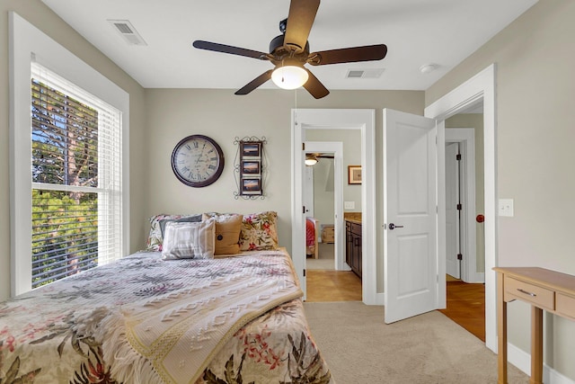 bedroom featuring ceiling fan, connected bathroom, and light colored carpet