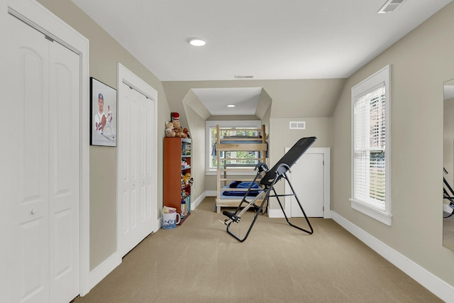 workout room with light carpet and vaulted ceiling