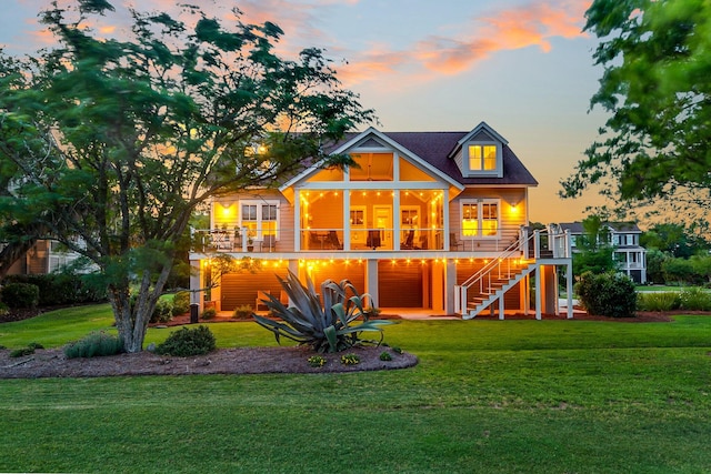 back house at dusk featuring a lawn