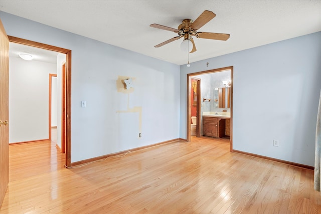 unfurnished bedroom featuring ensuite bath, light wood-type flooring, baseboards, and a ceiling fan