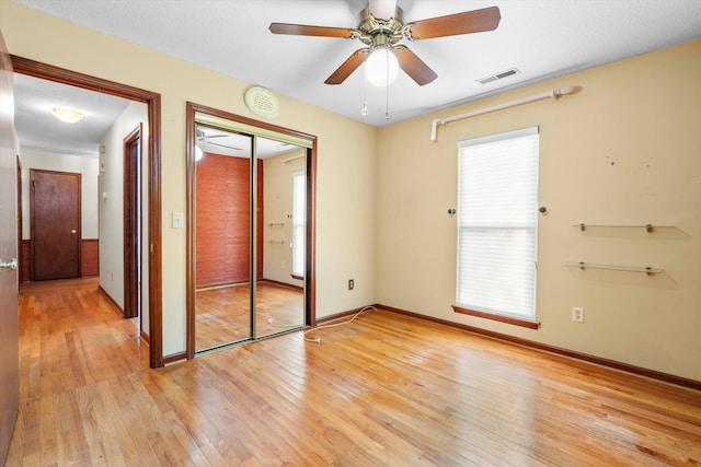 unfurnished bedroom featuring light wood-type flooring, baseboards, visible vents, and a closet