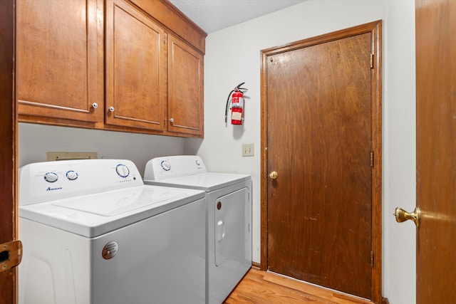 washroom with washer and clothes dryer, cabinet space, and light wood finished floors