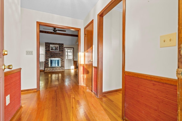 corridor featuring a wainscoted wall and light wood-style flooring