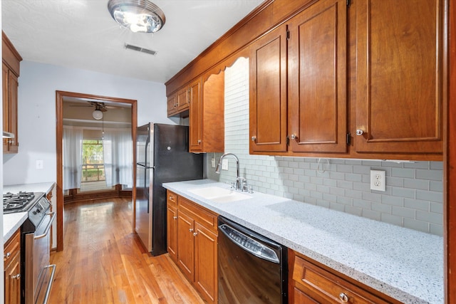 kitchen with brown cabinetry, visible vents, appliances with stainless steel finishes, and a sink