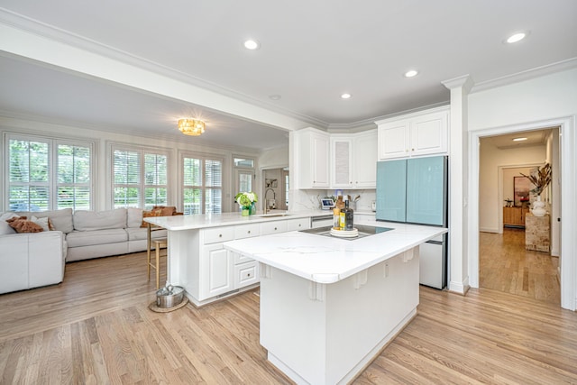 1143 Sea Eagle Watch, Charleston, SC 29412 - kitchen with a kitchen bar, a peninsula, ornamental molding, black electric cooktop, and light wood-type flooring