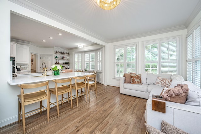 1143 Sea Eagle Watch, Charleston, SC 29412 - kitchen with crown molding, a peninsula, a kitchen bar, light wood-type flooring, and white cabinetry