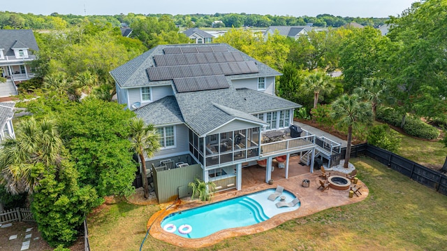 1143 Sea Eagle Watch, Charleston, SC 29412 - back of property with roof with shingles, a fire pit, a sunroom, roof mounted solar panels, and a fenced backyard